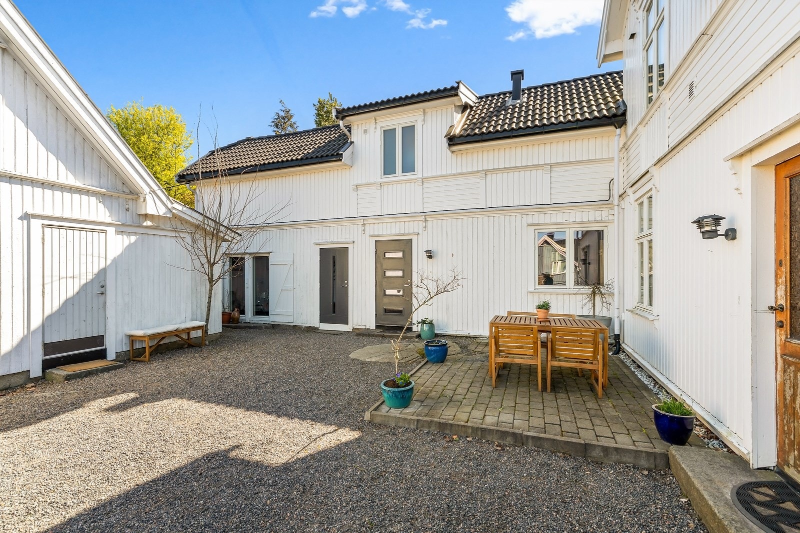 På inngangsiden av huset er det en gruslagt gårdsplass med uteplass. Her er det adkomst til "butikken", "musikkrommet" samt 1 - og 2 etasje. Galleribilde