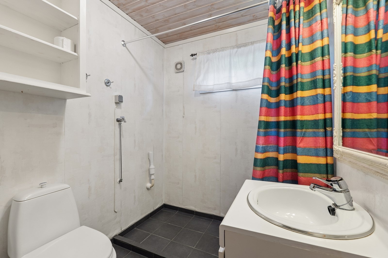 Bad/vaskerom med fliser på gulv. Våtromstapet på vegg og panel i tak. Rommet har servant, toalett og dusjløsning. Opplegg for vaskemaskin. Ventilert med mekanisk ventilasjon på vegg. TG3 i rapporten. Galleribilde