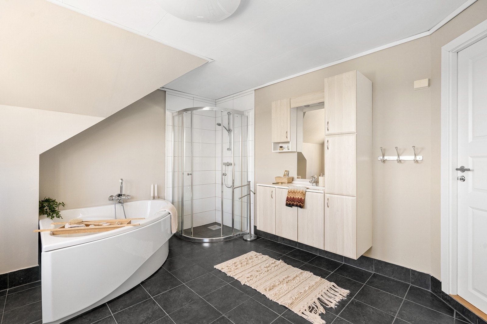 Badet i 2.etasje inneholder hjørnebadekar, dusjhjørne og stor baderomsinnredning. Galleribilde
