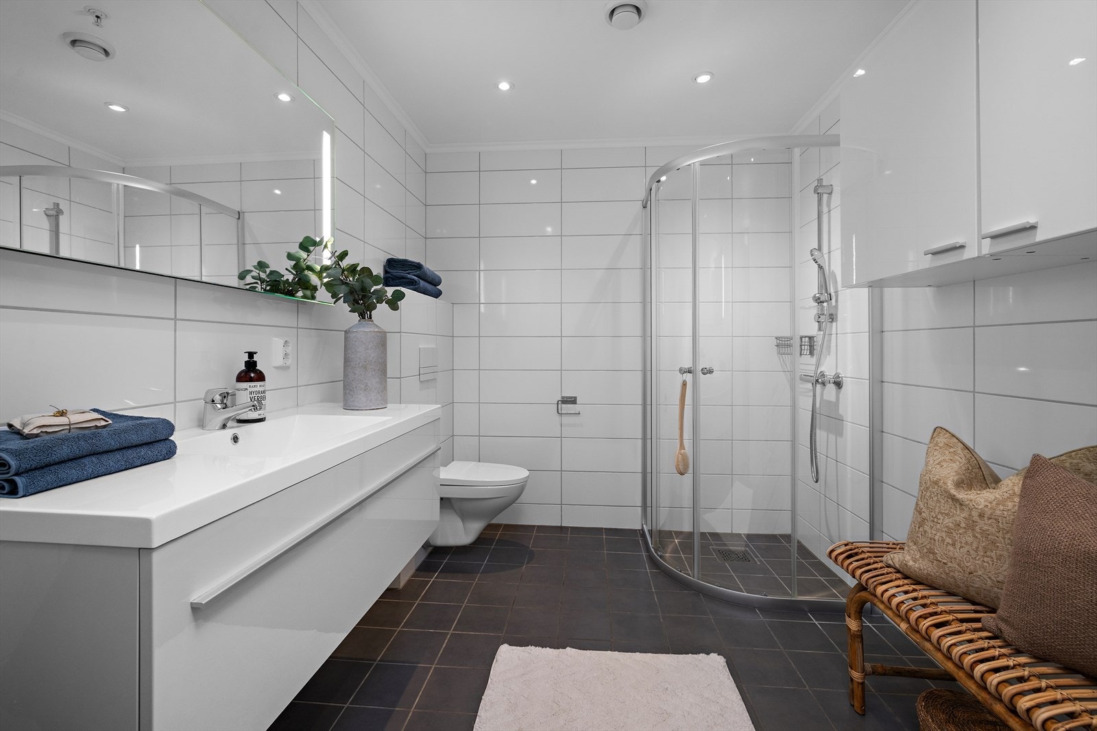 Badet er utstyrt med dusjhjørne med innfellbare dører og varme i gulvet. Galleribilde