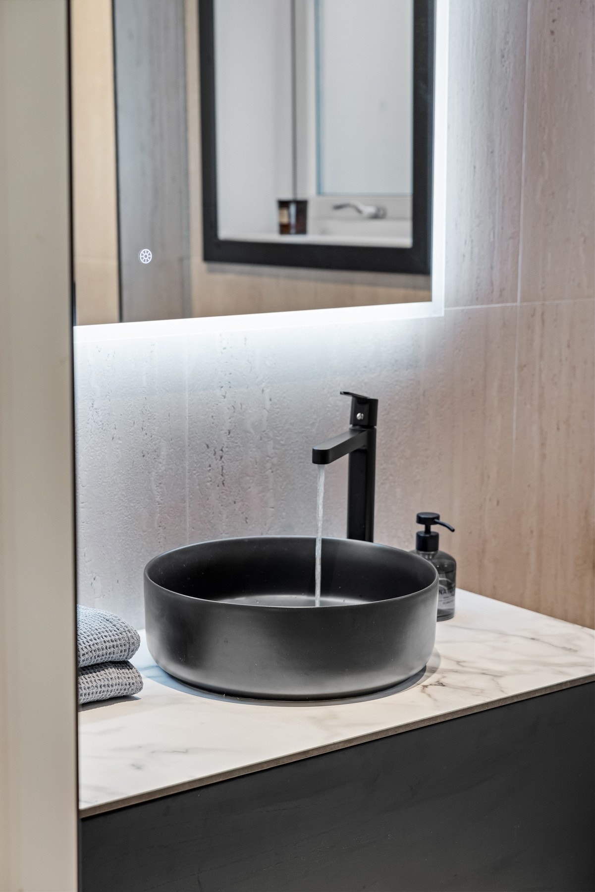 Badet er innredet med vegghengt servantskap med ovenpåliggende servant og ett-greps armatur, speil med belysning, dusjnisje med glassdører og regnfallsdusj, samt vegghengt toalett med innebygget sisterne. Galleribilde