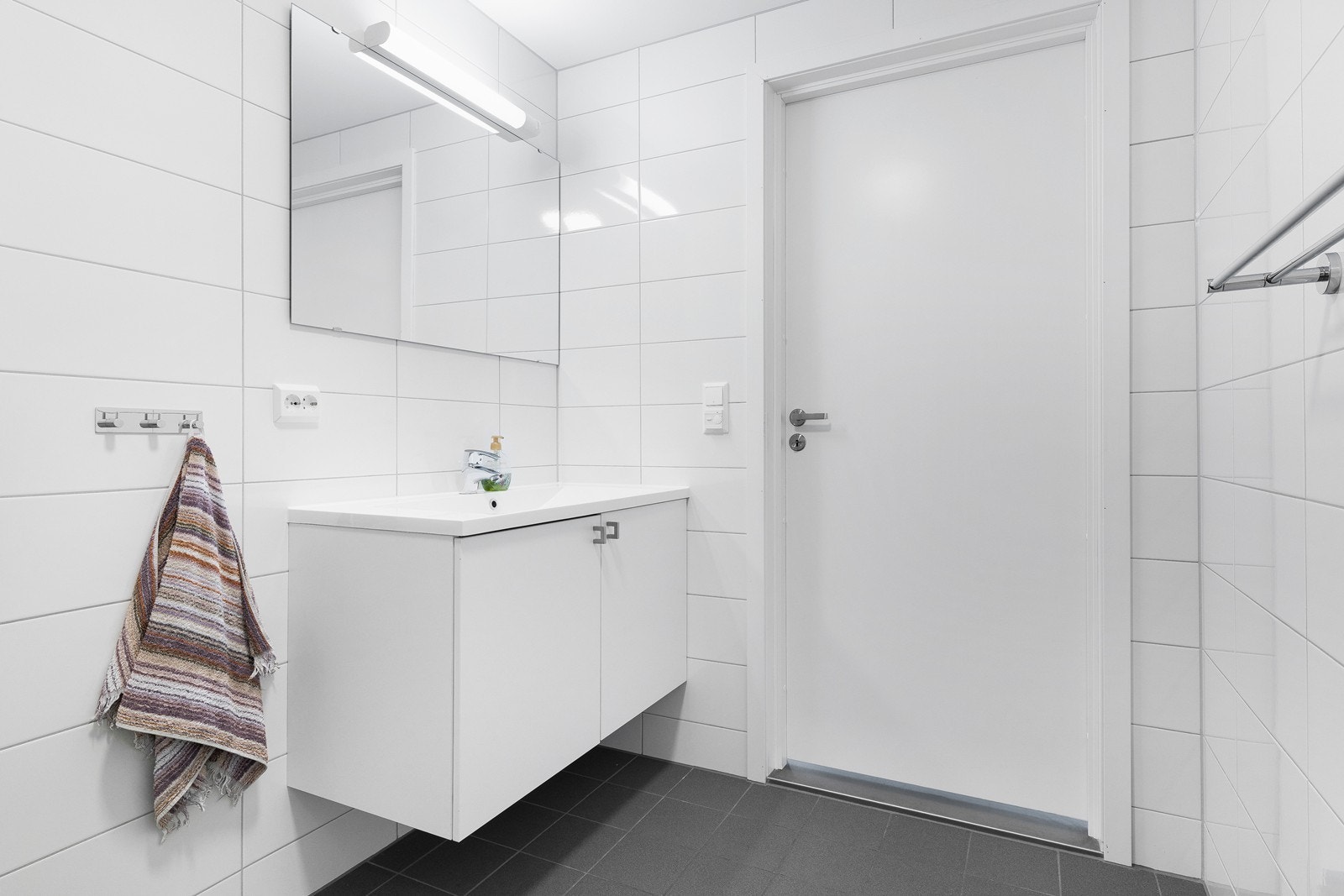 Badet er innredet med vegghengt toalett, innfellbare dusjvegger og servant med underskap og speil. Galleribilde