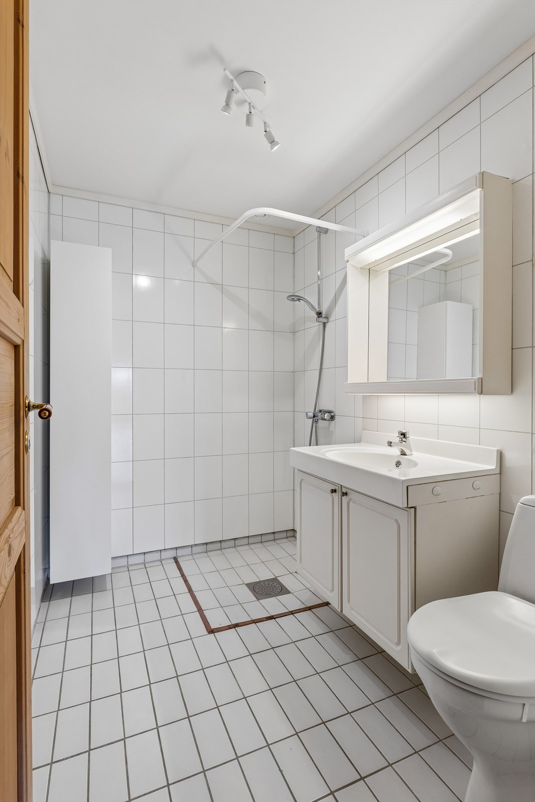 Badet har flislagt gulv med gulvvarme, servant med underskap og dusj. Galleribilde