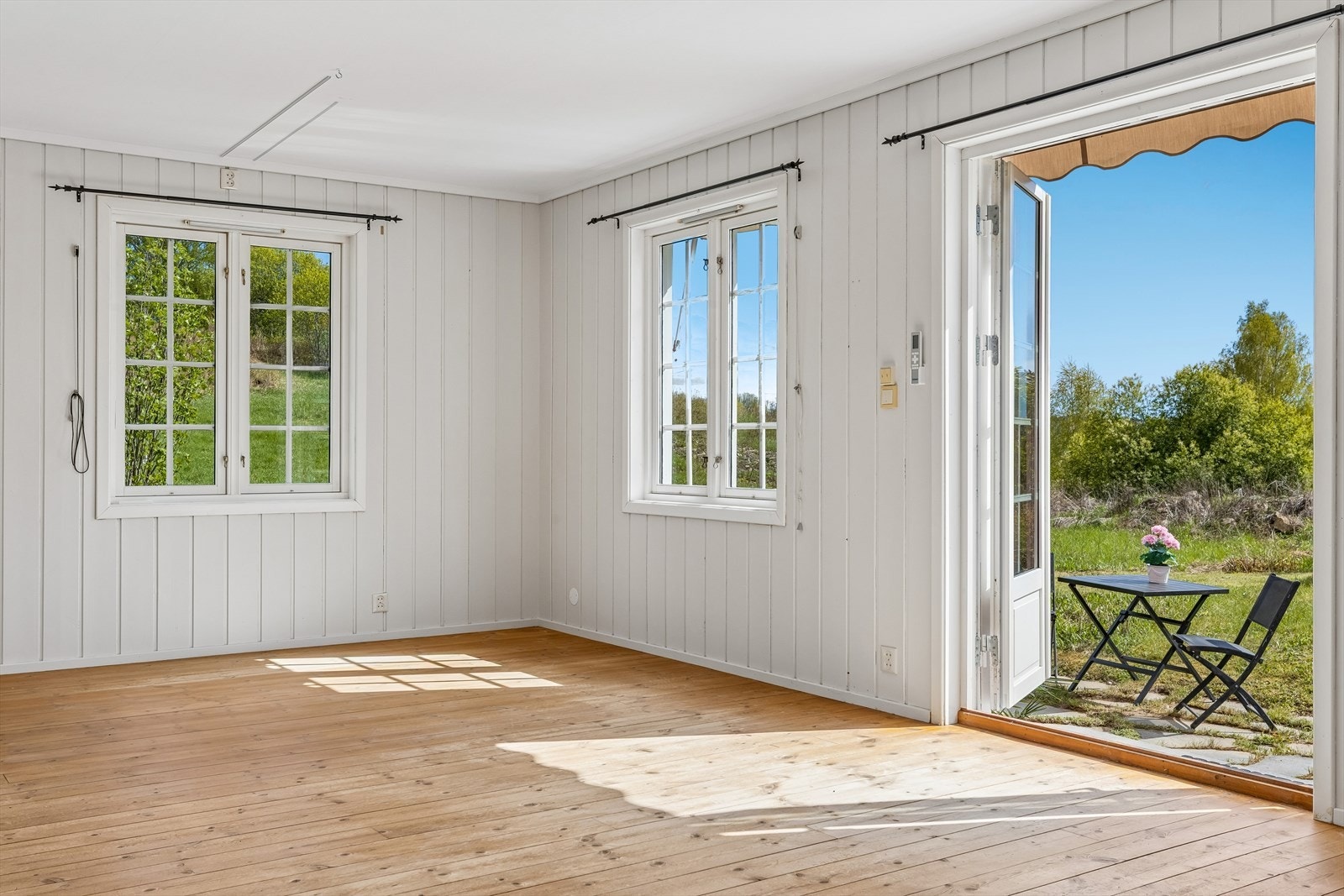 Den tofløyede terrassedøren i tre åpner opp mot den sørvendte uteplassen. Galleribilde