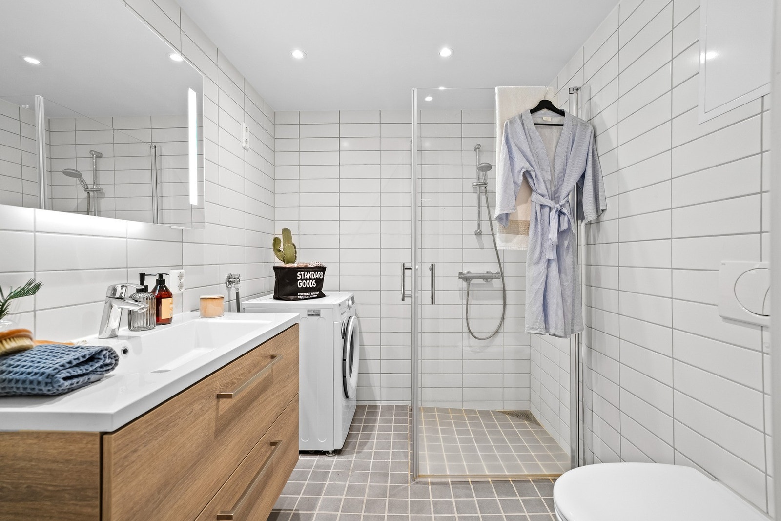 Badet fremstår pent med flislagte overflater, vannbåren gulvvarme og mørk innredning. Galleribilde