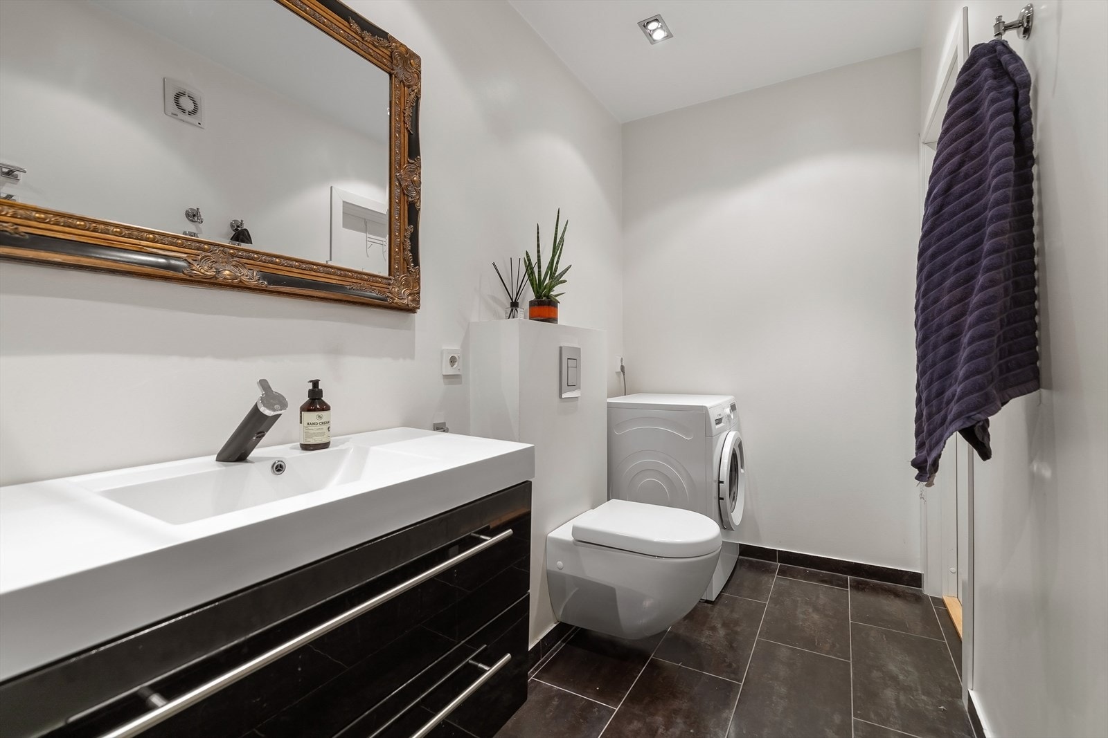 Badet har vegghengt toalett, moderne innredning og opplegg for vaskemaskin. Galleribilde