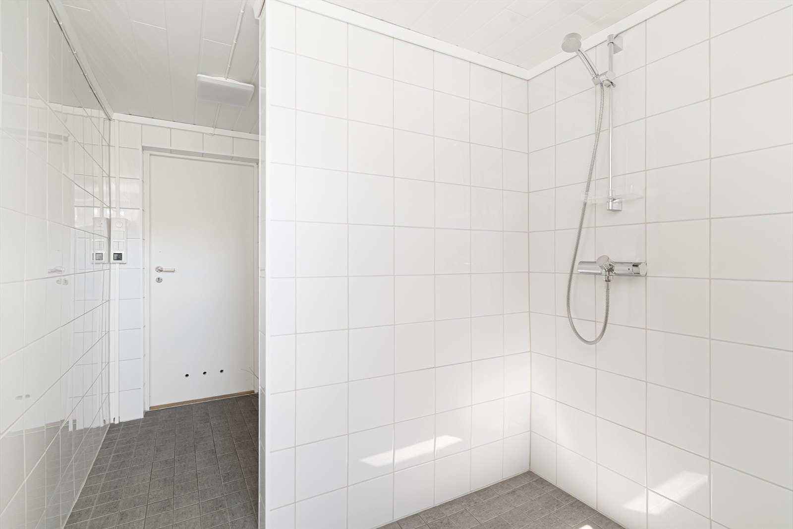 Romslig dusjløsning med flislagte overflater og elektrisk avtrekksvifte i yttervegg. Galleribilde