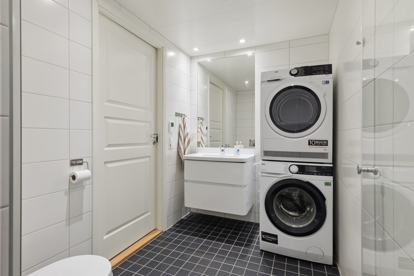 Badet i 2. etg. ligger i tilknytning til gang, og brukes som kombinert bad/vaskerom. Badet inneholder ellers moderne servantinnredning, stort speil, toalett og dusjnisje. Galleribilde