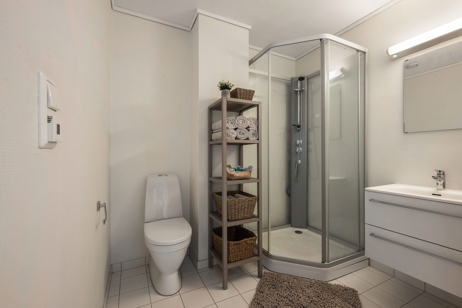 Badet har dusjkabinett, vask med skuffer til oppbevaring og toalett. Galleribilde