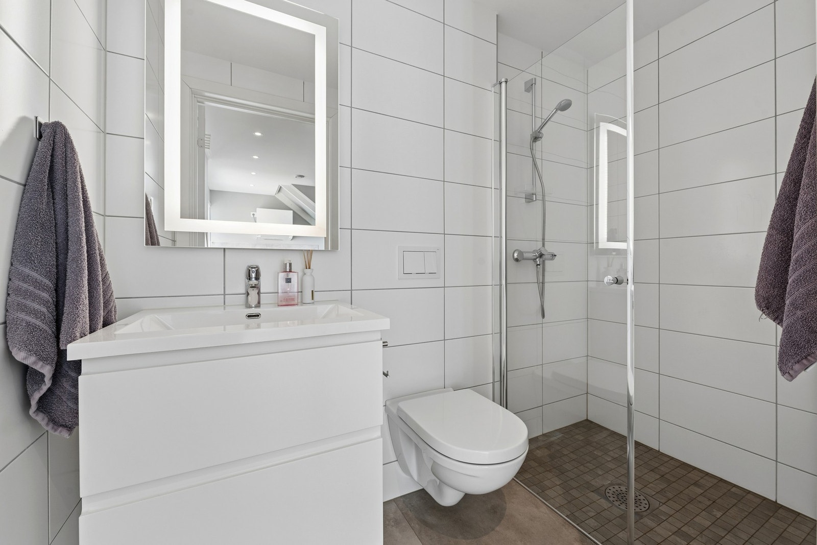Badet fremstår moderne og delikat med flislagte overflater og tidsriktig innredning. Galleribilde