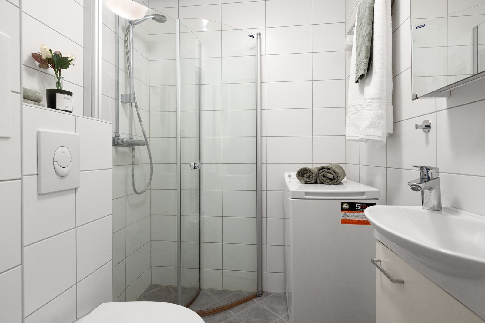 Et pent og moderne baderom fra 2014 med foldbare glassdører, vegghengt toalett og servant med skapinnredning. Galleribilde