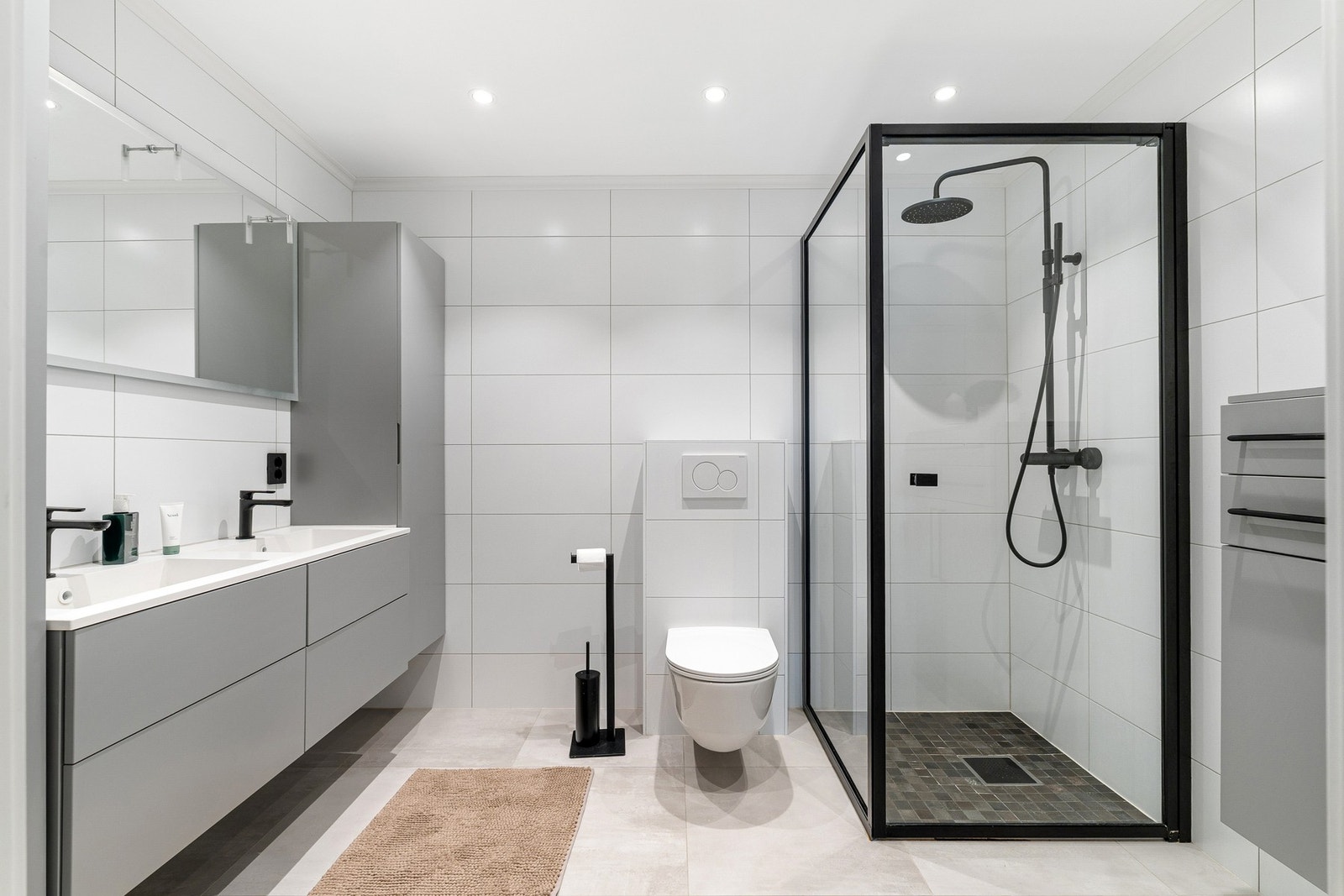 Moderne flisbelagt bad med elektriske varmekabler i gulv og downlights fra tak. Galleribilde