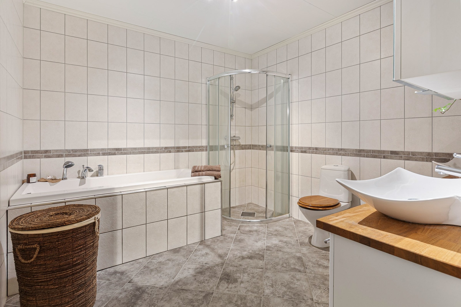 Hovedbadet i underetasjen er helfliset og har både innmurt badekar og et separat dusjhjørne med skyvedører. Galleribilde