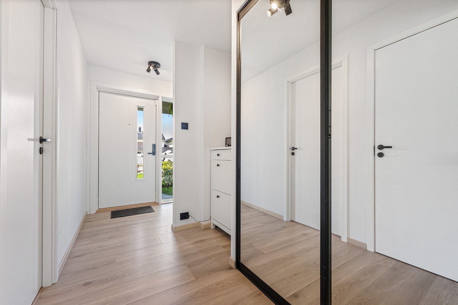 Entré med laminat på gulv, lyse vegger og himling. Plass til å henge av yttertøy i skyvedører med speilfronter. Galleribilde