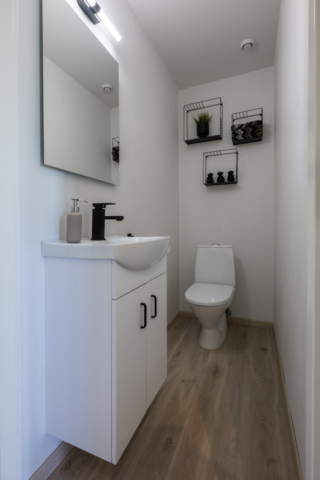 Gjestewc ligger ved entré og har laminat på gulv, toalett, malte vegger og enkel servant. Galleribilde