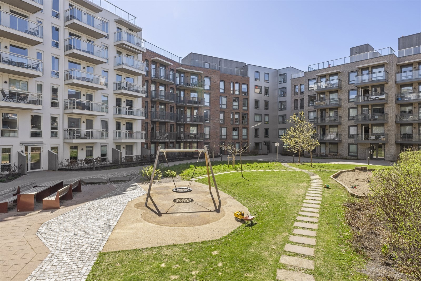 Koselig og pent opparbeidet fellesareal med gressarealer, lekeapparater og sitteplasser. Galleribilde