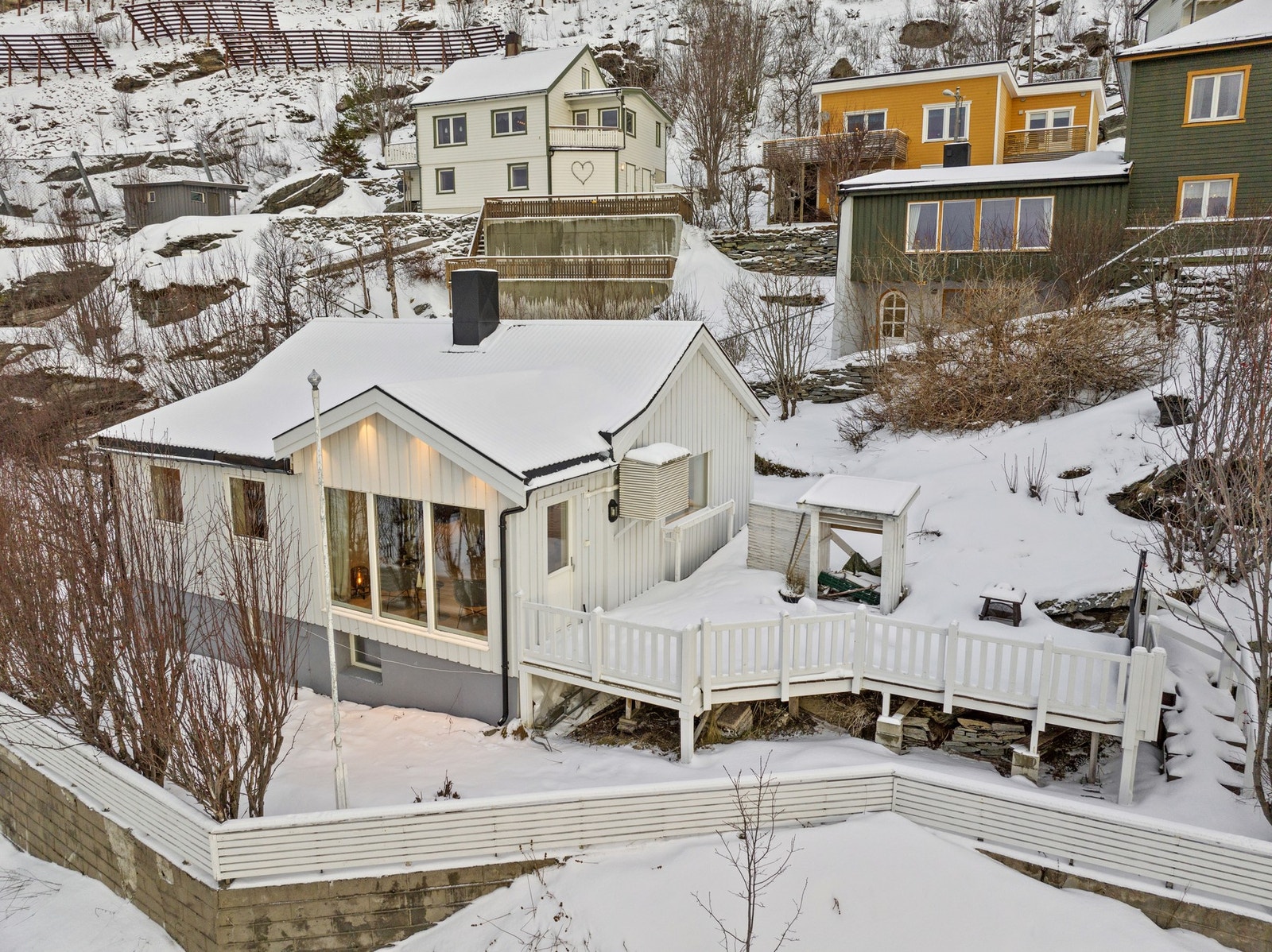 Eiendommen er rammet inn av gjerde og har en stor treterrasse. Galleribilde