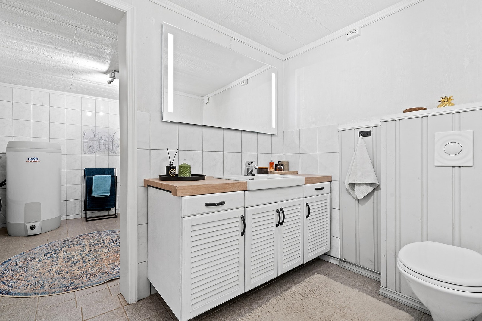 Baderomsinnredning med servant, oppbevaringsplass og speil med belysning. Galleribilde
