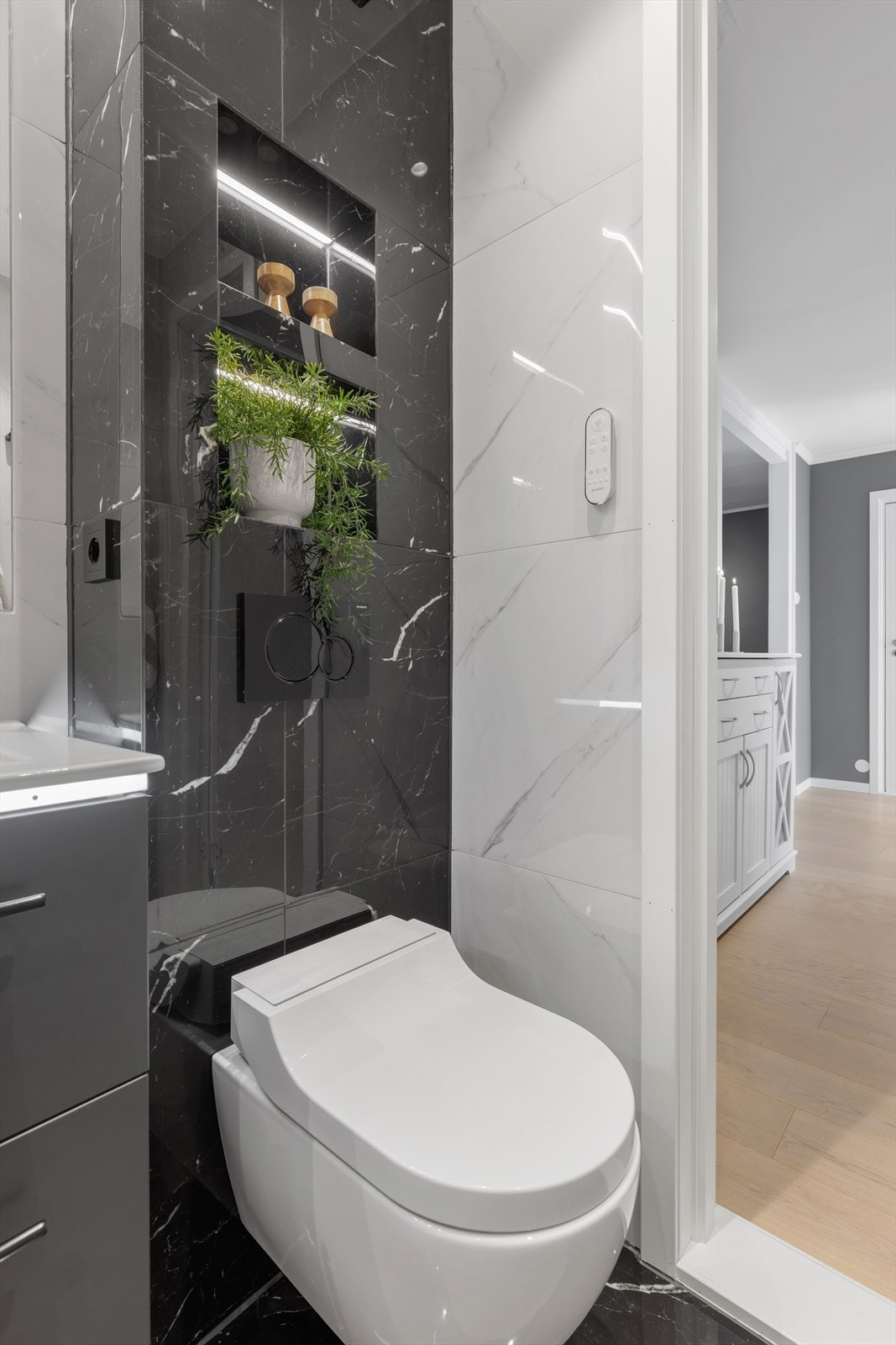 Badet har et vegghengt, automatisk spyletoalett fra Geberit og en elegant, innebygget hylle i dusjsonen. Galleribilde