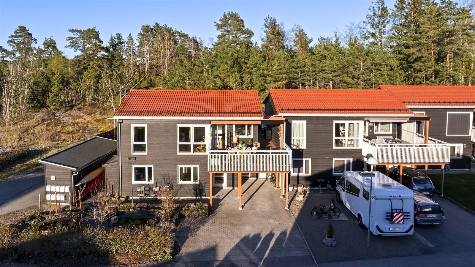 Sportsboden ved carporten er romslig og perfekt for sykler og sportsutstyr, mens utstyrsboden langs husveggen gir ekstra plass til hageredskaper. Galleribilde