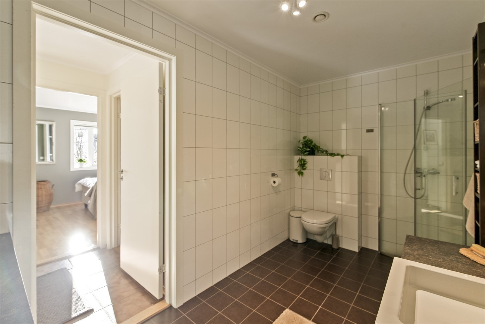 Badet i denne etasjen er praktisk innrettet med flislagt gulv, dusjhjørne og opplegg for vaskemaskin. Galleribilde