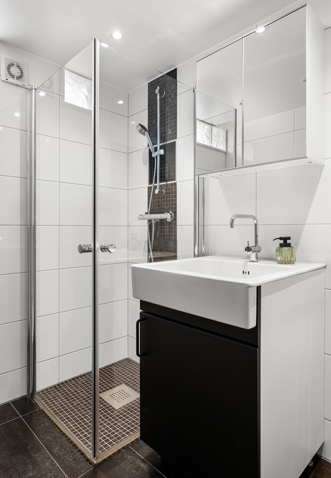 Badet er innredet med servantinnredning, speil, dusjhjørne med glassdører og vegghengt toalett. Galleribilde