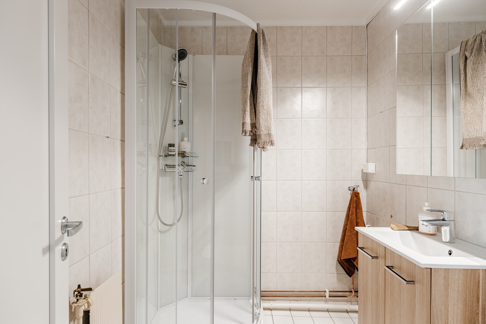 Funksjonelt bad med flislagte overflater og opplegg for vaskemaskin. Badet har ny innredning fra 2026. Galleribilde