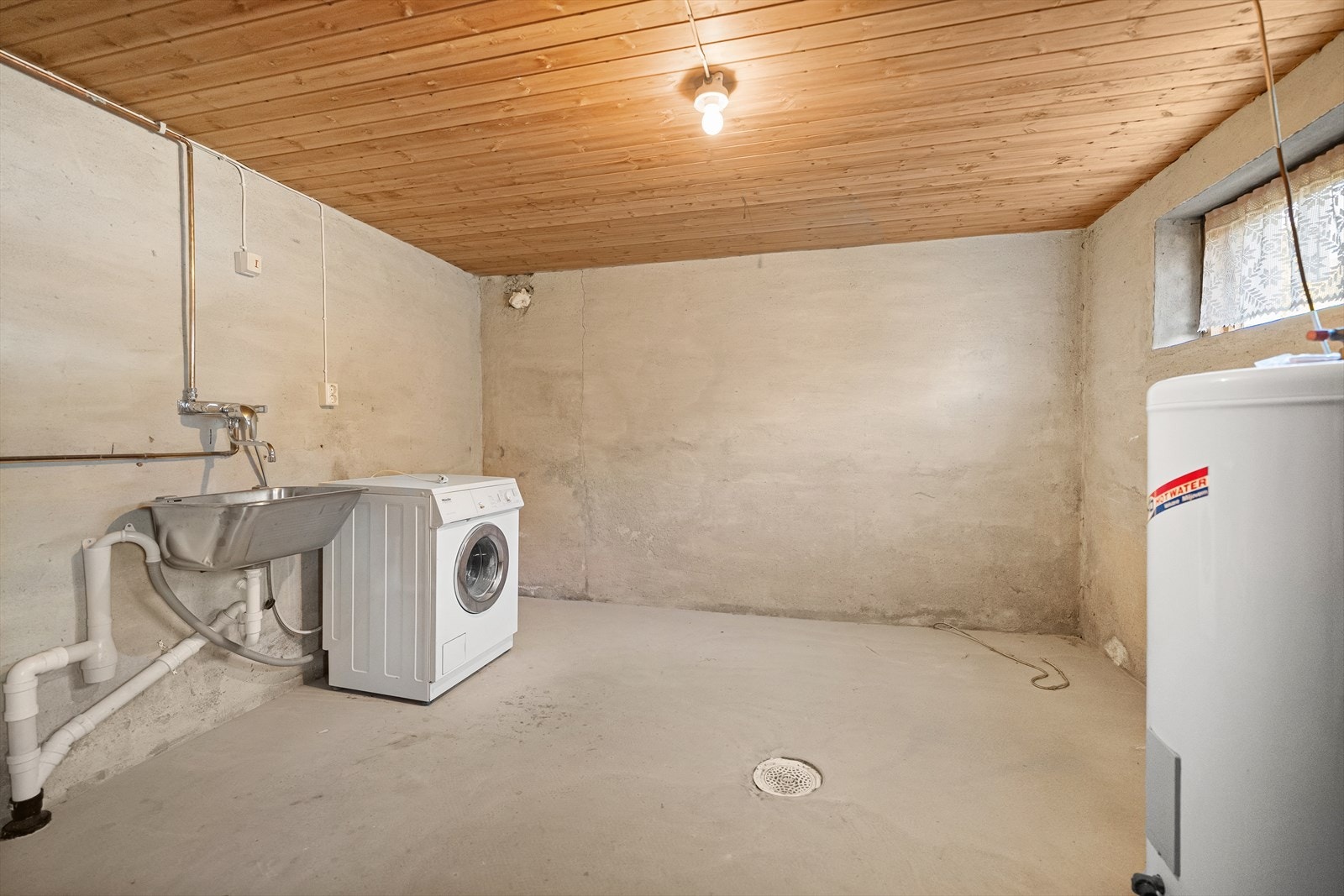 Felles vaskerom i kjelleren med opplegg for vaskemaskin og en varmtvannstank på ca. 200 liter. Galleribilde