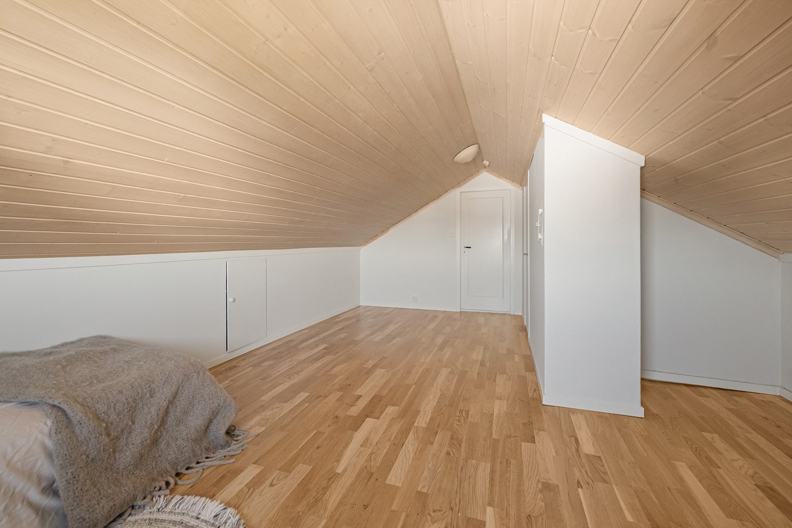 Innredet loftsrom med parkett på gulv og panel i tak. Galleribilde