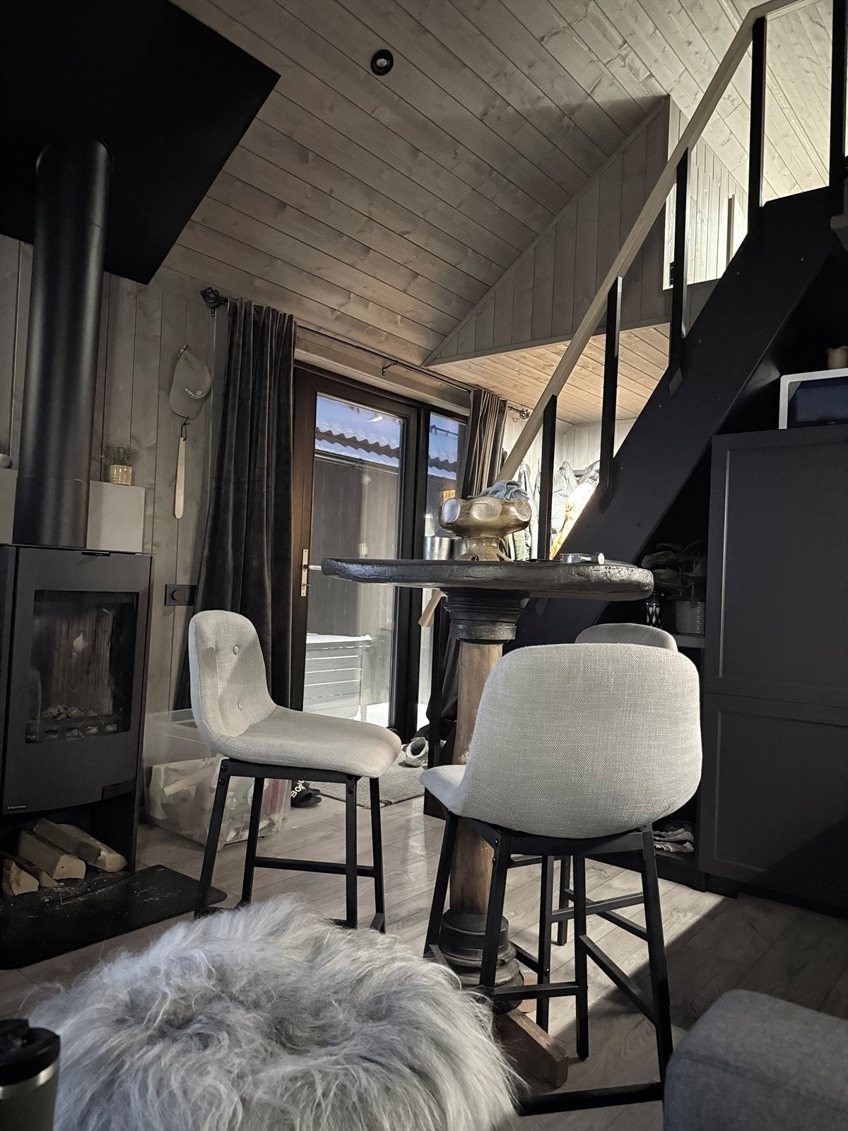 Hus 2: Stue med stor takhøyde og store vindusflater fra gulv til tak mot terrasse, åpen kjøkkenløsning og trapp til hems Galleribilde