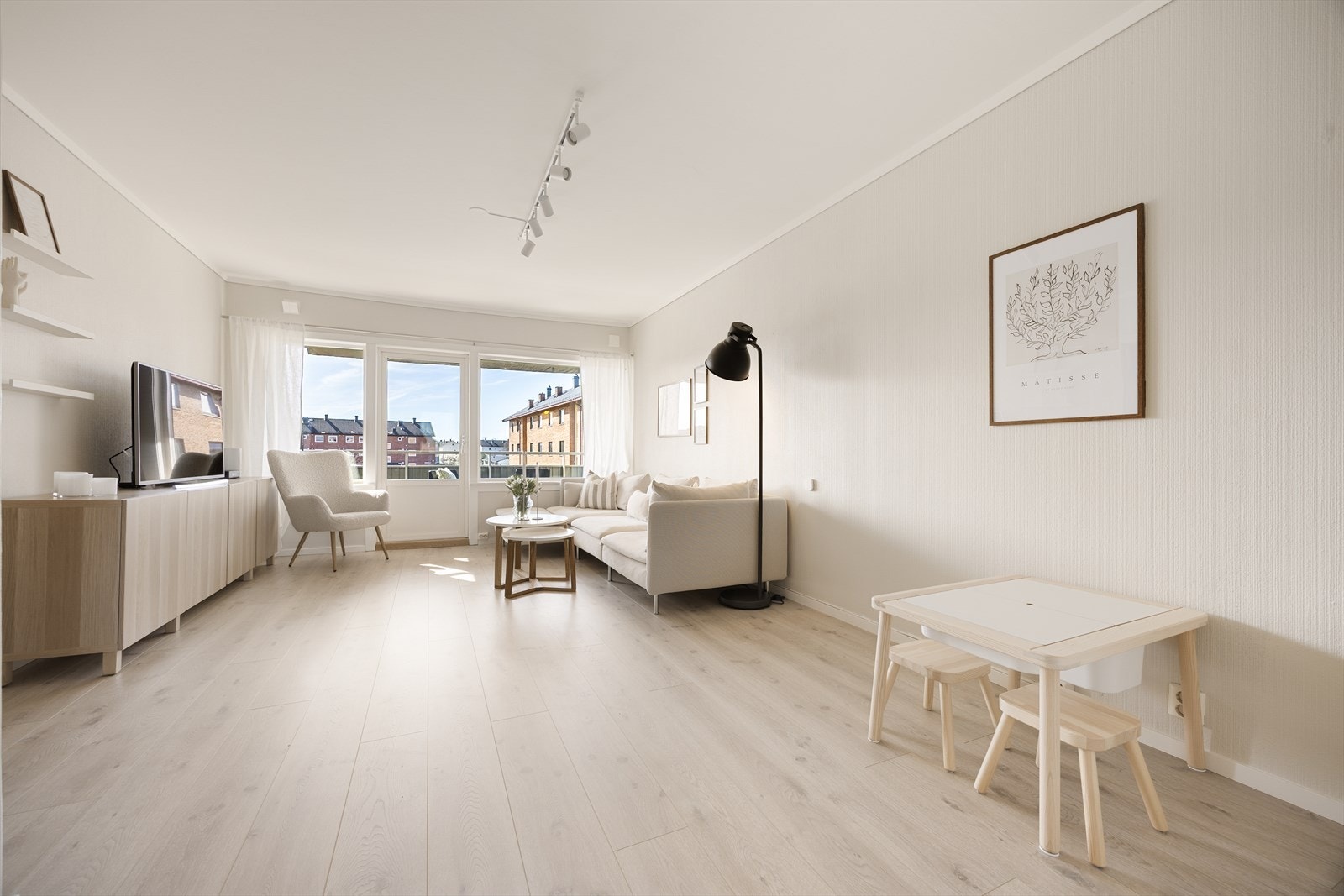 De lyse overflatene og det nye laminatgulvet skaper en helhetlig og tidsriktig atmosfære i stuen. Galleribilde