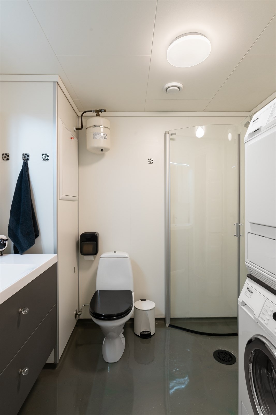 Her er det dusjhjørne med glassdører, toalett, nyere baderomsinnredning med nedfelt vask og opplegg for både vaskemaskin og tørketrommel. Galleribilde