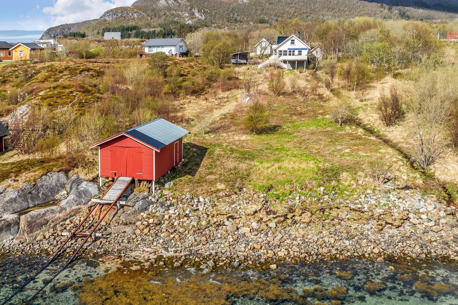 Naustet i forgrunn, deretter fritidsboligen, utestue, anneks og redskapshus. Galleribilde