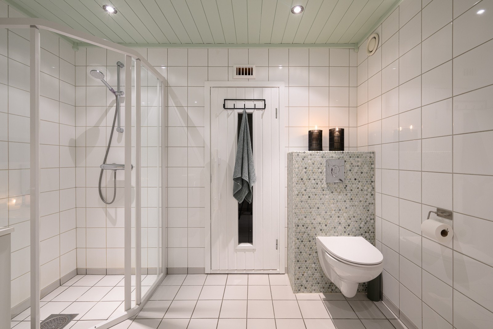 Badet er helfliset og utstyrt med gulvvarme, vegghengt toalett og dusjhjørne med innfellbare vegger. Galleribilde