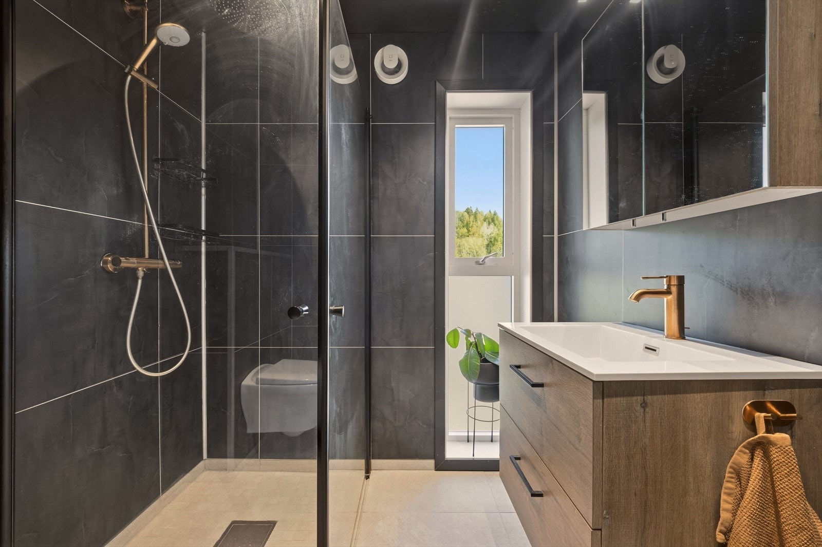 Badet er utstyrt med heldekkende servant med underskap, speilskap, dusjnisje og toalett Galleribilde