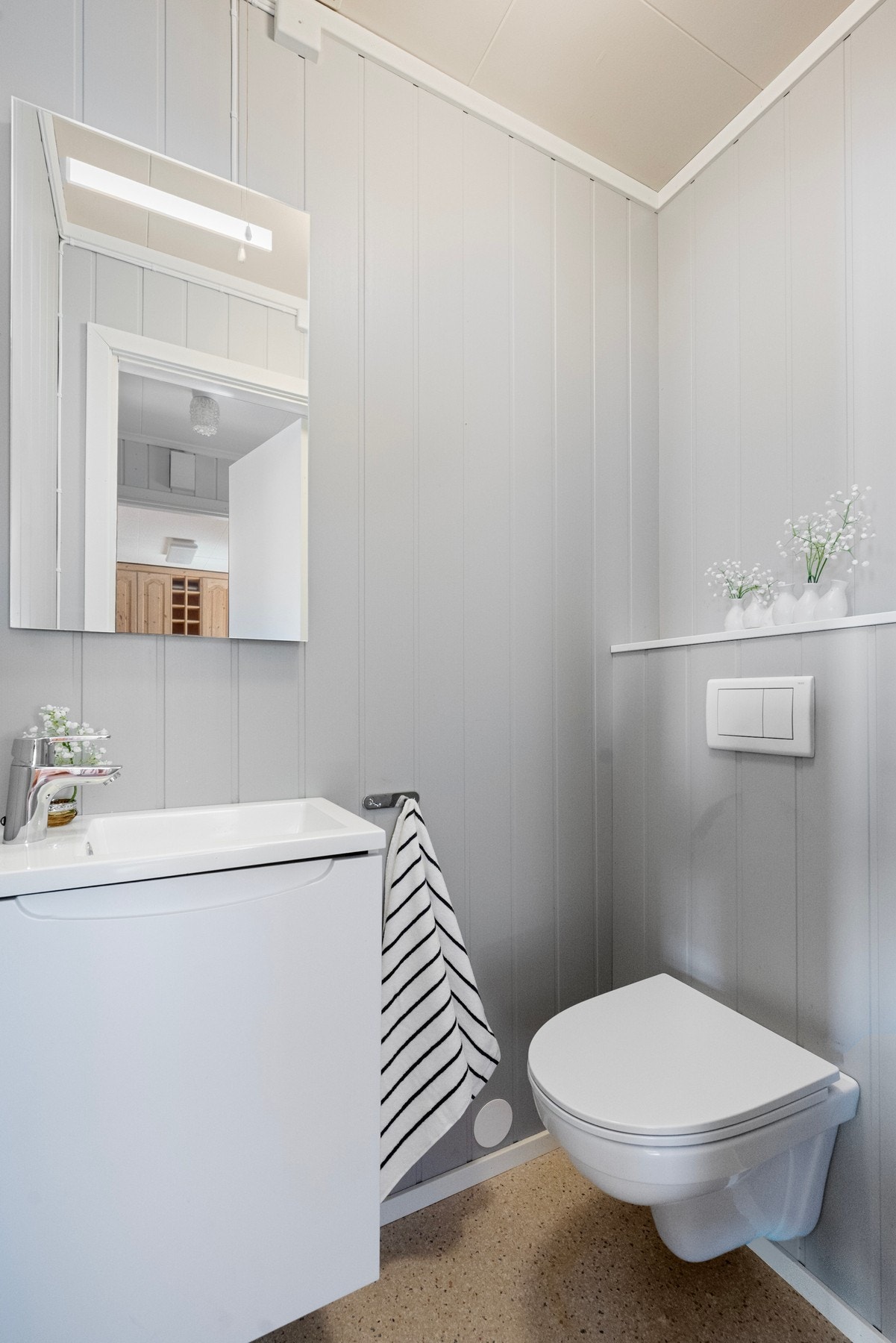 Separat toalettrom med laminatgulv og panelplater på vegger. Rommet er utstyrt med WC og servant med skap Galleribilde