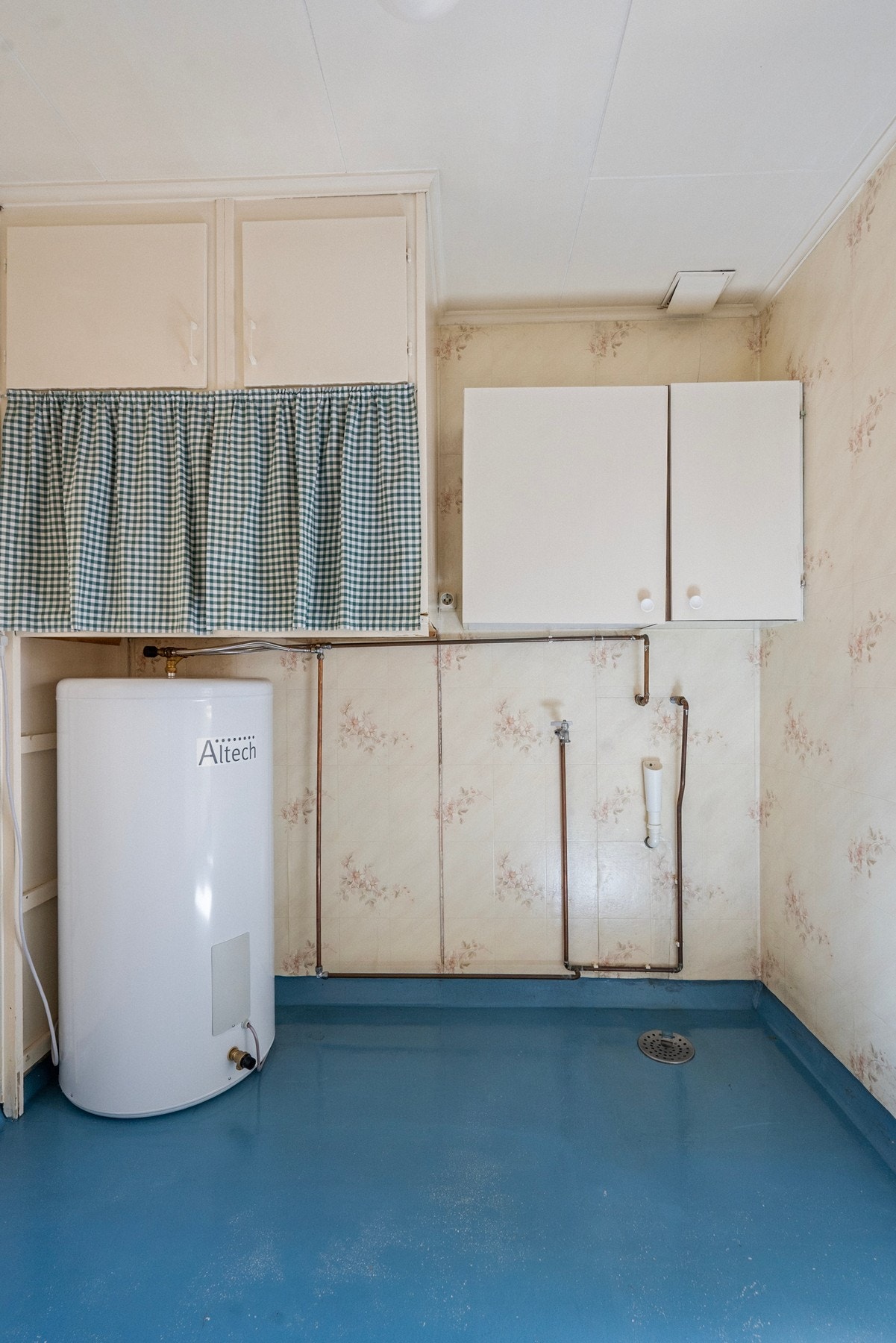 Rommet har gulvbelegg, tapet på vegger og opplegg for vaskemaskin. Varmtvannsbereder er plassert her, og ventilasjon skjer via ventil i vegg. Galleribilde