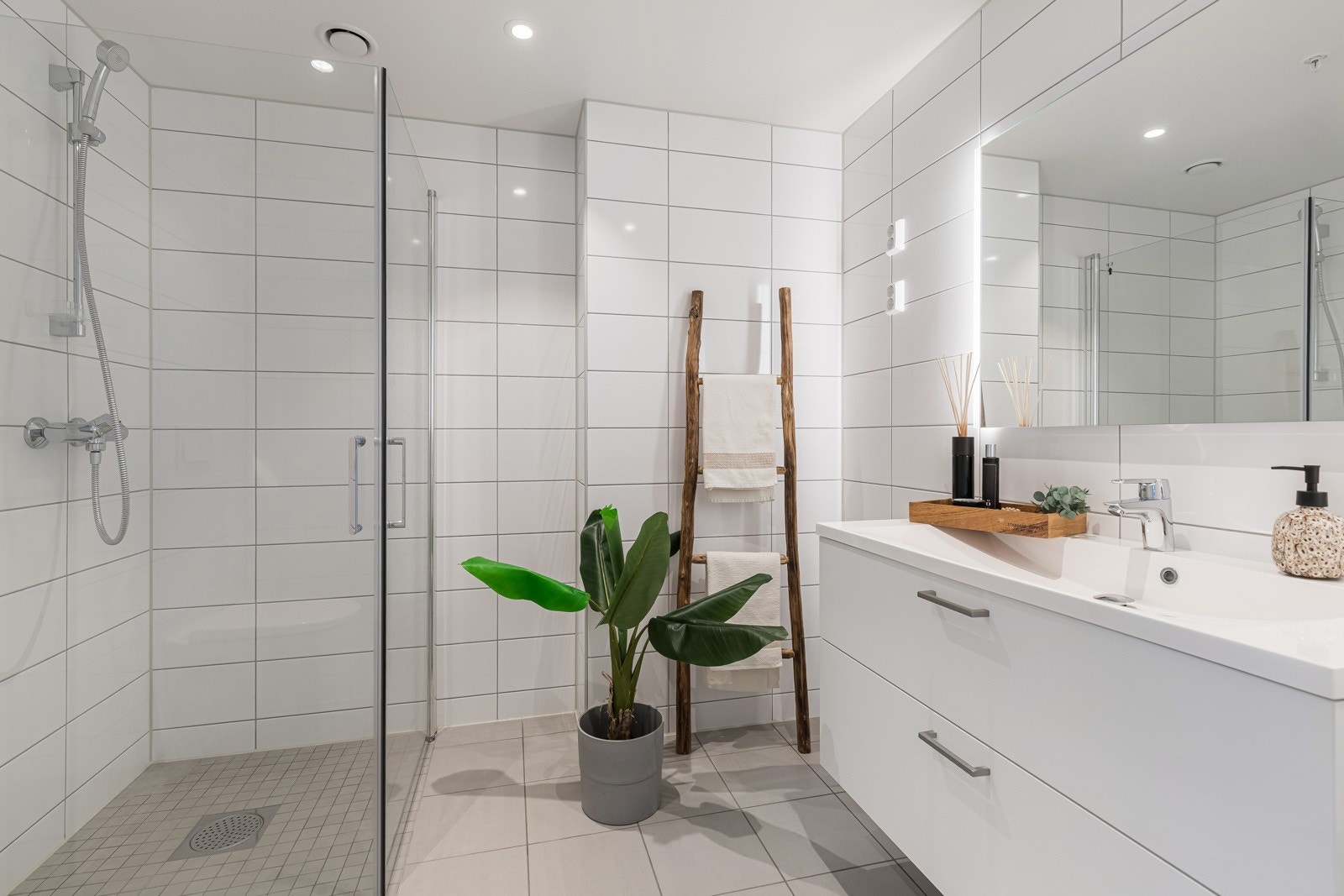 Romslig, flislagt bad/WC med dusjnisje, downlights og baderomsinnredning med rikelig oppbevaringsplass Galleribilde