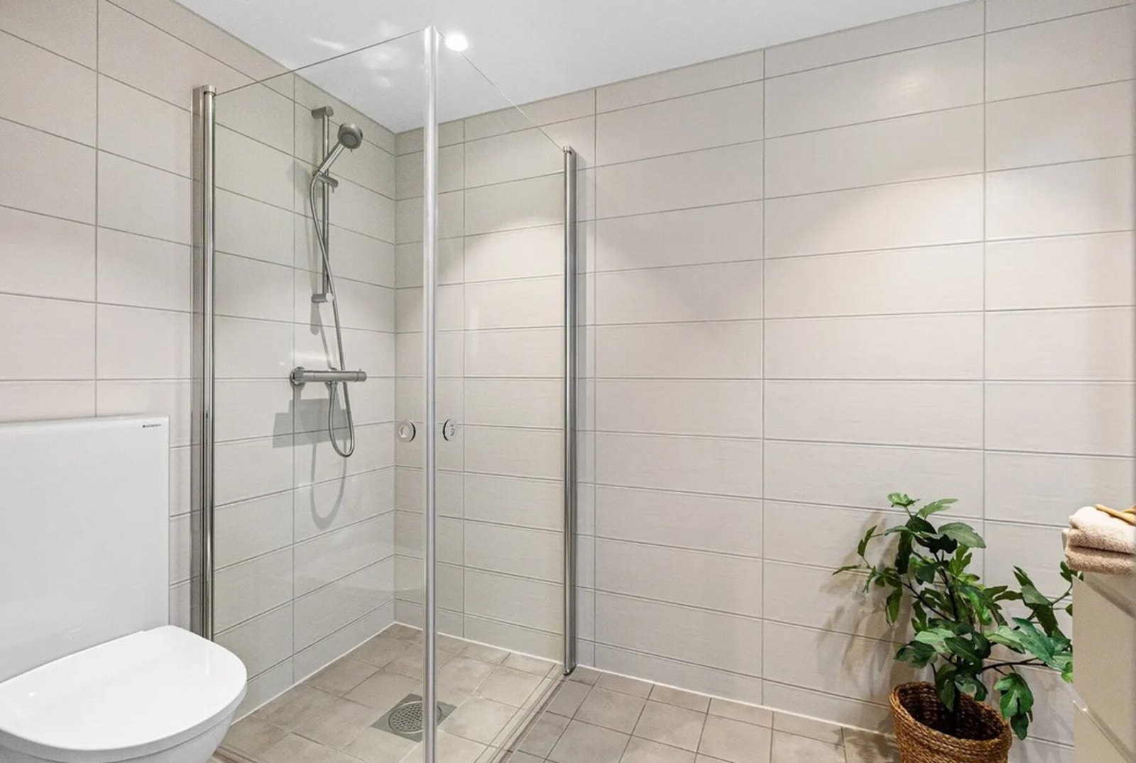Badet er innredet med åpen dusjløsning som gir en romslig og lett tilgjengelig dusjsone. Galleribilde