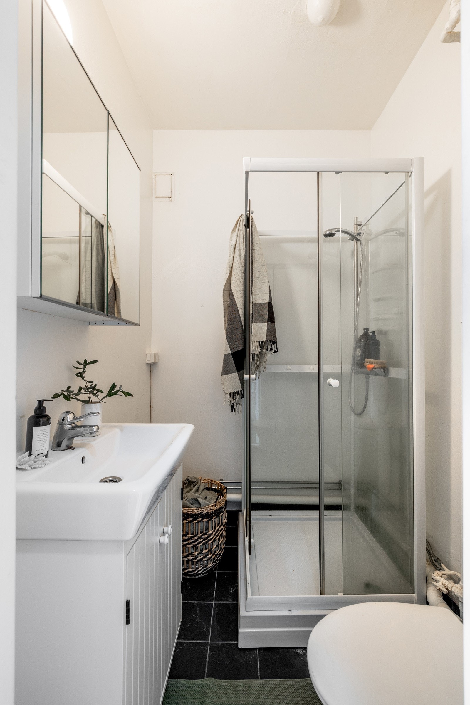 Leiligheten har et bad med moderniseringbehov - Badet er flislagt og har dusjkabinett, toalett, servantinnredning og speilskap Galleribilde