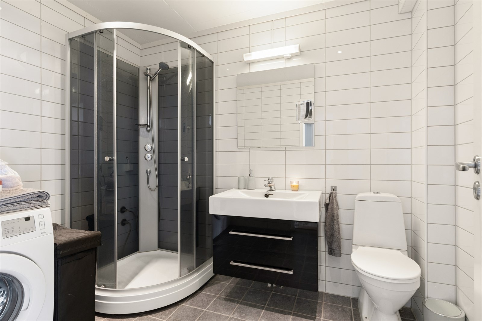Badet i første etasje er utstyrt med et servantskap, gulvmontert toalett og et dusjkabinett. Galleribilde