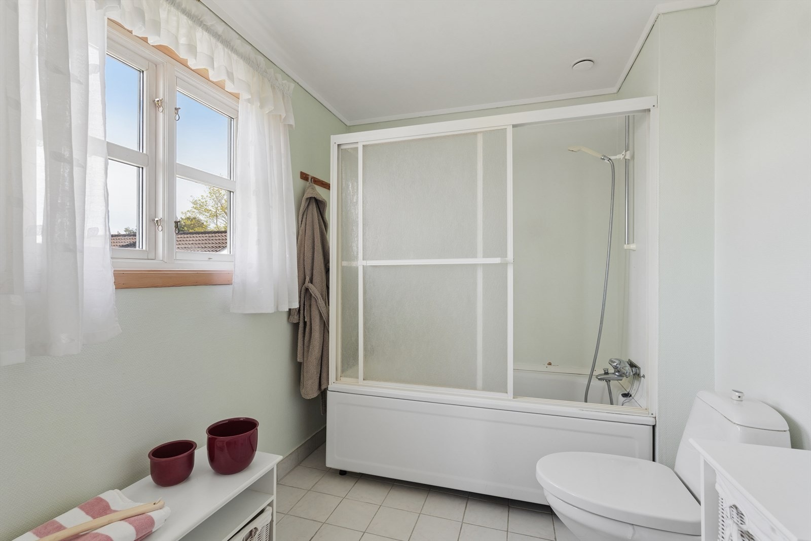 Gulvstående toalett. Badet har flislagt gulv. Galleribilde