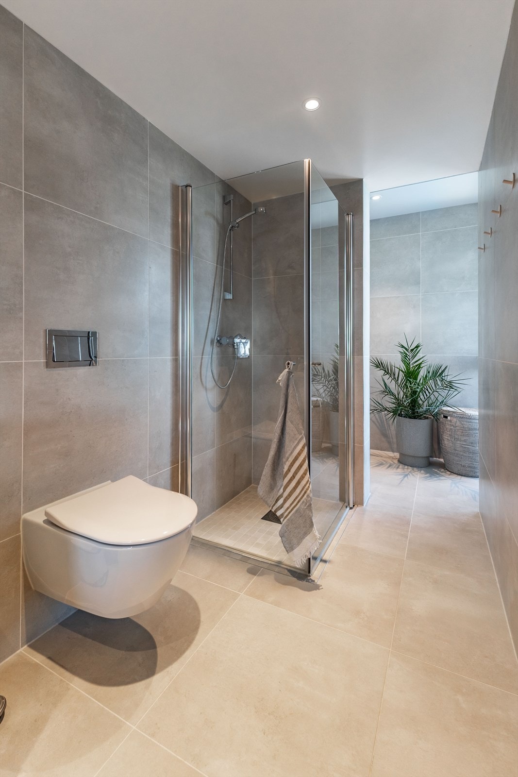 Badet er utstyrt med vegghengt toalett og et dusjhjørne med innfellbare glassdører. Galleribilde