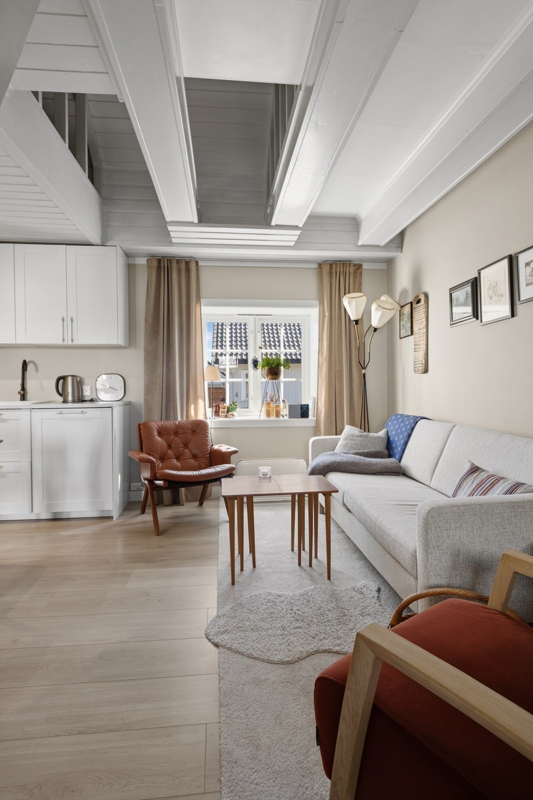 Vinduer slipper inn dagslys, og det malte paneltaket bidrar til rommets karakter. Galleribilde