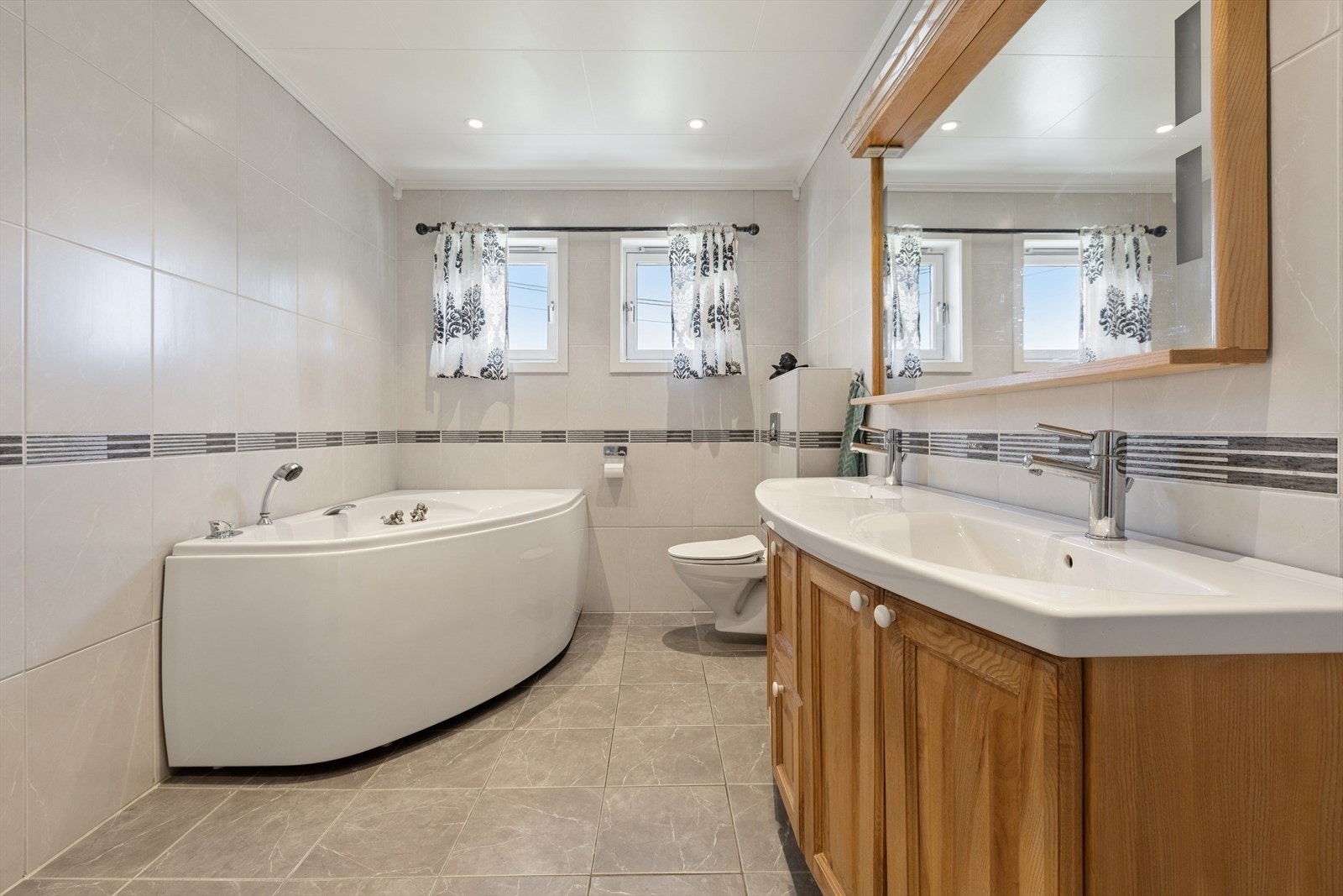 Badet i første etasje er utstyrt med både hjørnebadekar og dobbel servant i innredning. Galleribilde