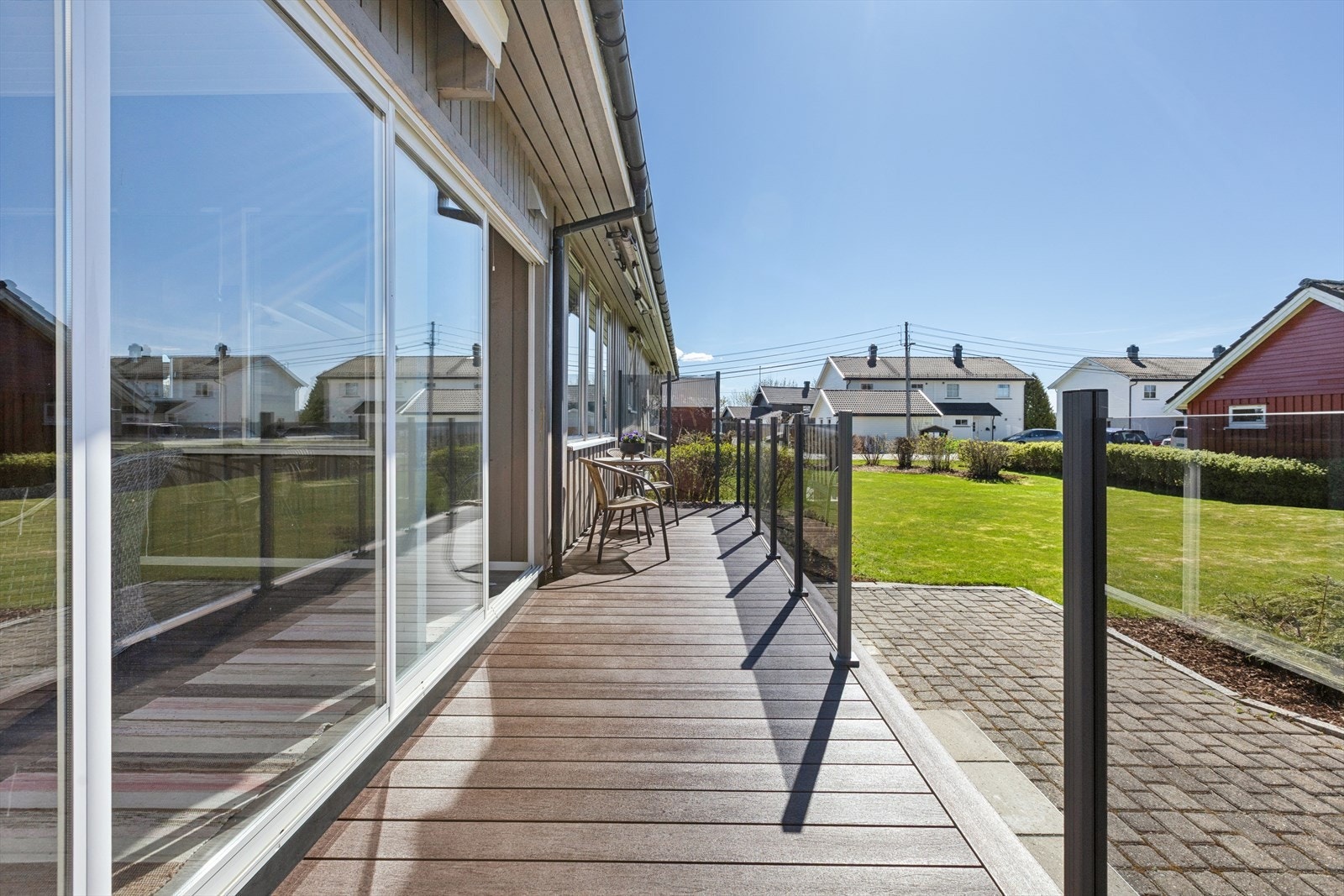 Terrasse med gulvbord av kompositt og rekkverk i glass, med utgang fra vinterhagen. Denne er ikke omsøkt. Galleribilde
