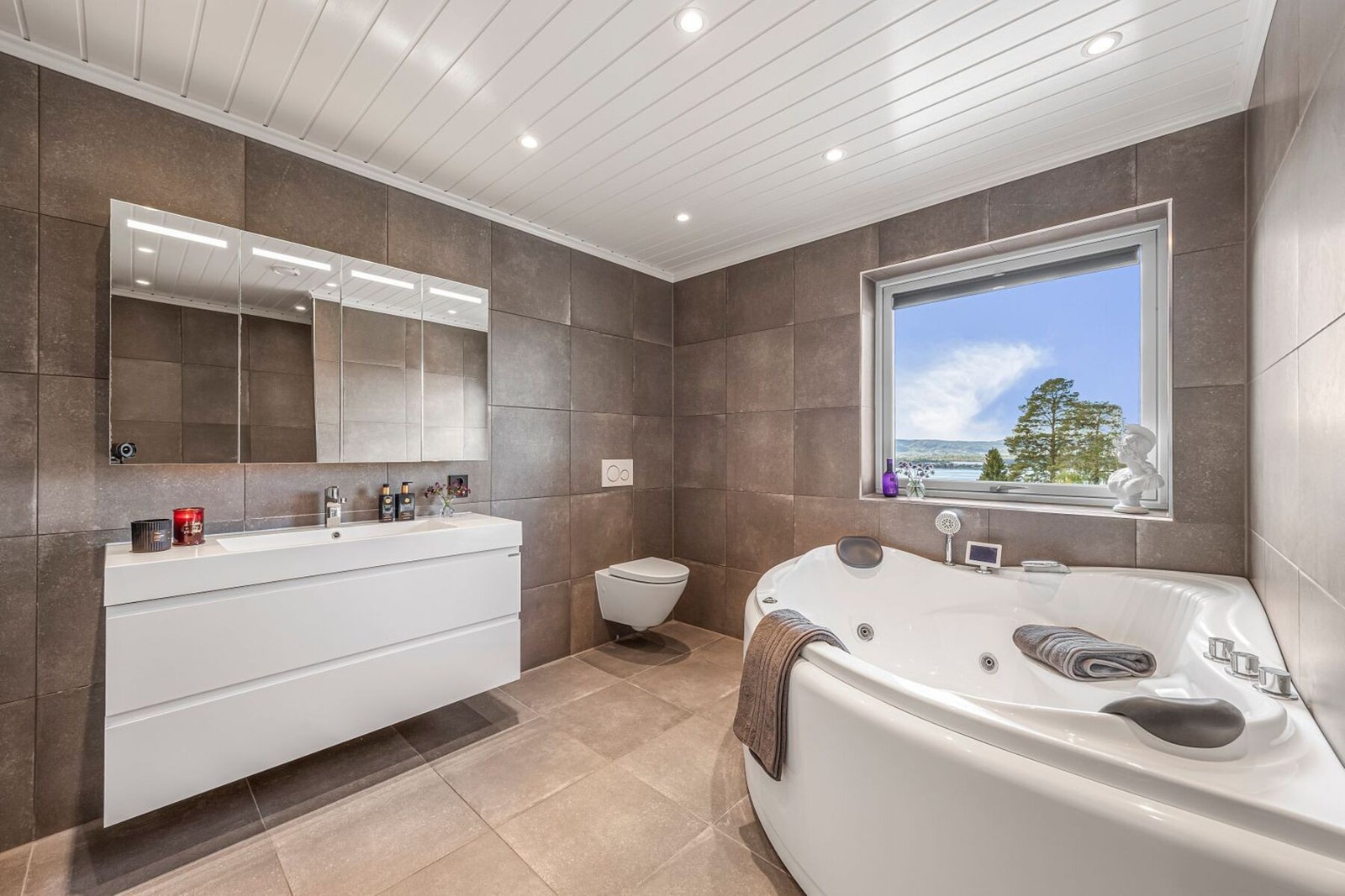 Stort og delikat flislagt bad med varmekabler i gulv som gir høy komfort. Badet fremstår som eksklusivt og spa-inspirert. Galleribilde