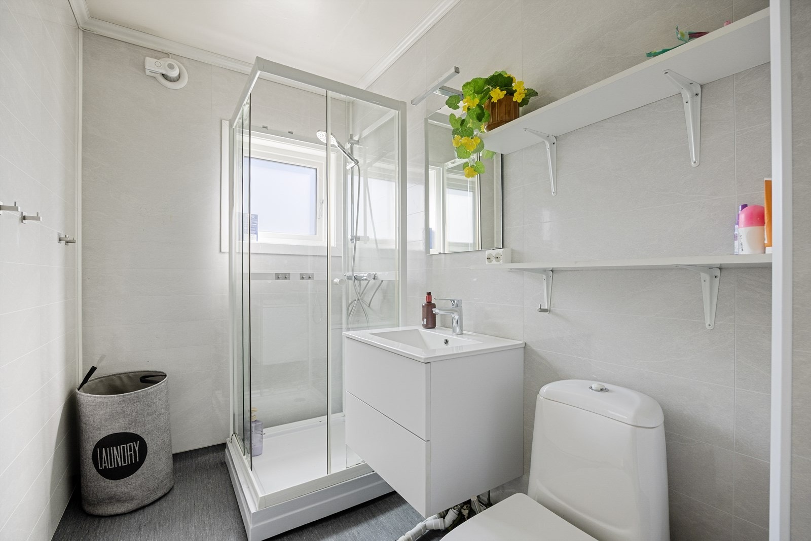 Badet i første etasje er utstyrt med dusjkabinett, servant i innredning og toalett. Veggene har baderomsplater. Galleribilde