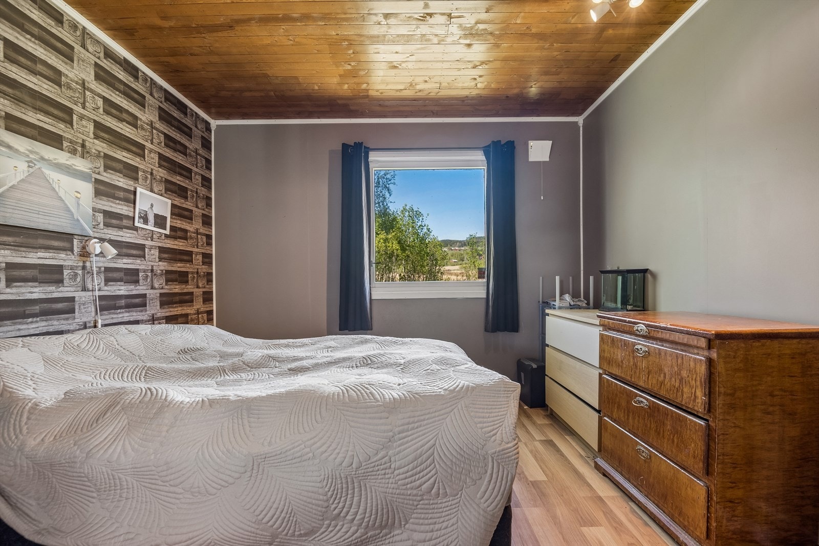Soverom med laminat på gulvet og trepanel i himlingen. Galleribilde