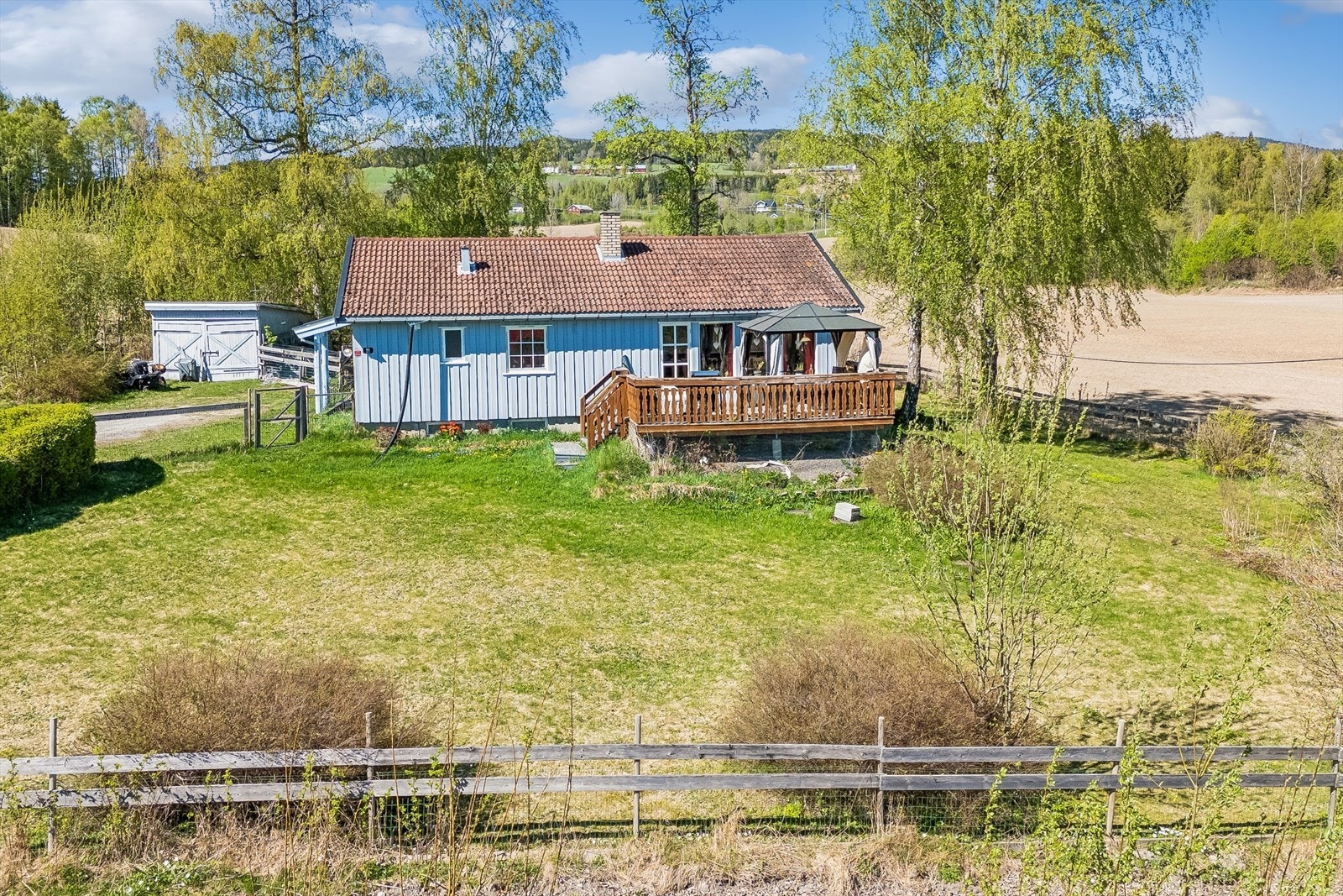 Eiendommen ligger i et område med spredt bebyggelse, omkranset av jorder og skog. Galleribilde